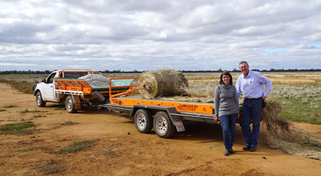 Patrick Daniher beside a Daniher Bale Feeder trailer that has unrolled a round bale